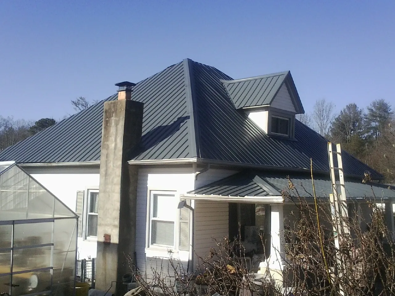 Dark blue standing seam metal roof on a white farmhouse with dormer — Slate & Tile Roof Repair by Roofing Brothers in Langhorne