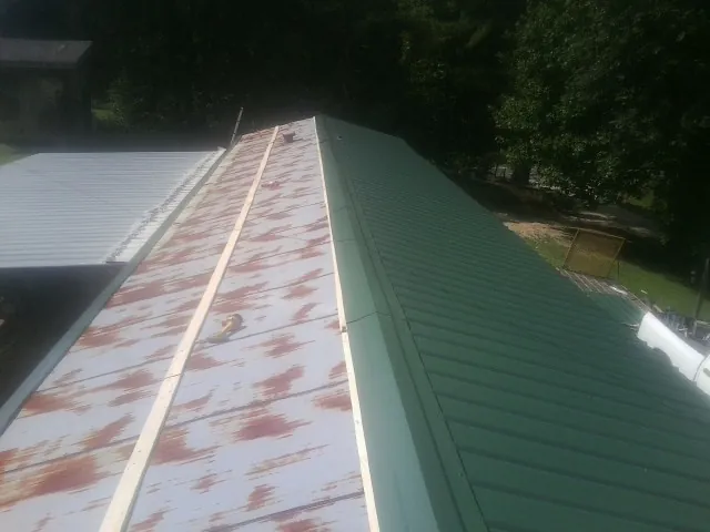 Old rusted panels beside newly installed green metal roofing — Wind Damage Roof Repair by Roofing Brothers in Langhorne