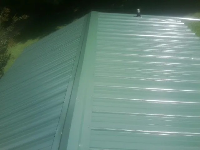 New green metal panels meeting at the ridge of a roof — Flat Roof Repair work by our crew in Langhorne