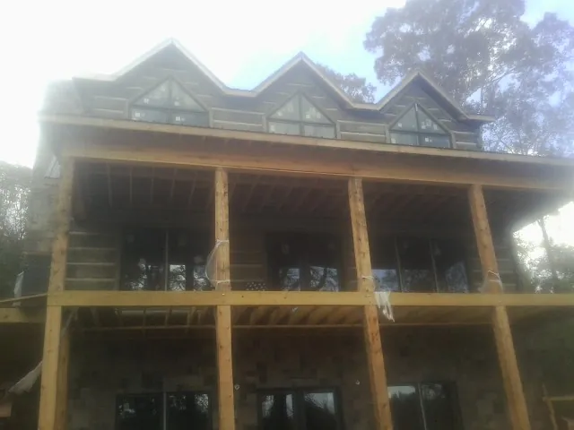 Dormers and porch framing on a large log home under construction — Roof Coating work by our crew in Langhorne