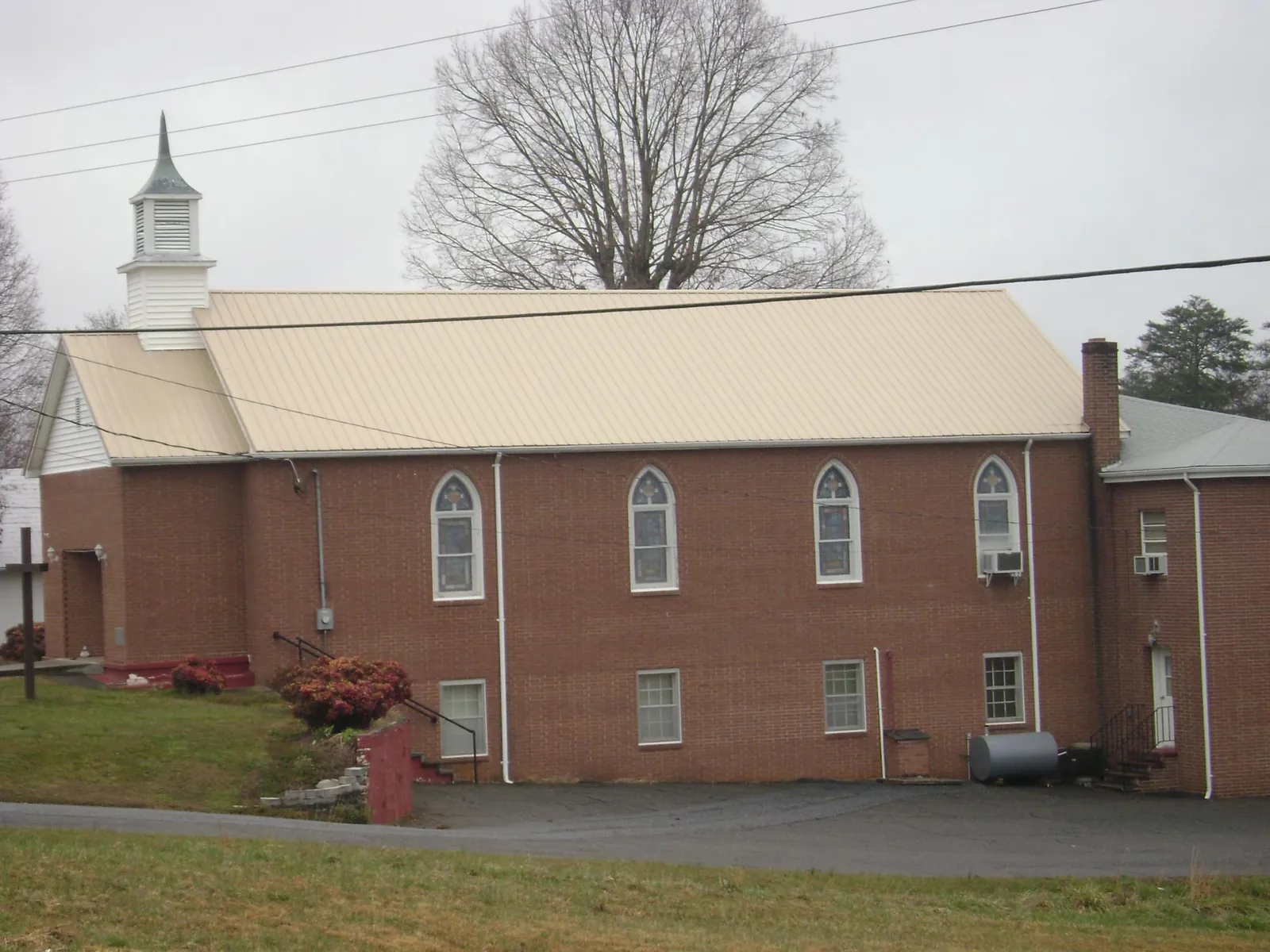 New tan metal roof on a brick church with a white steeple in Langhorne