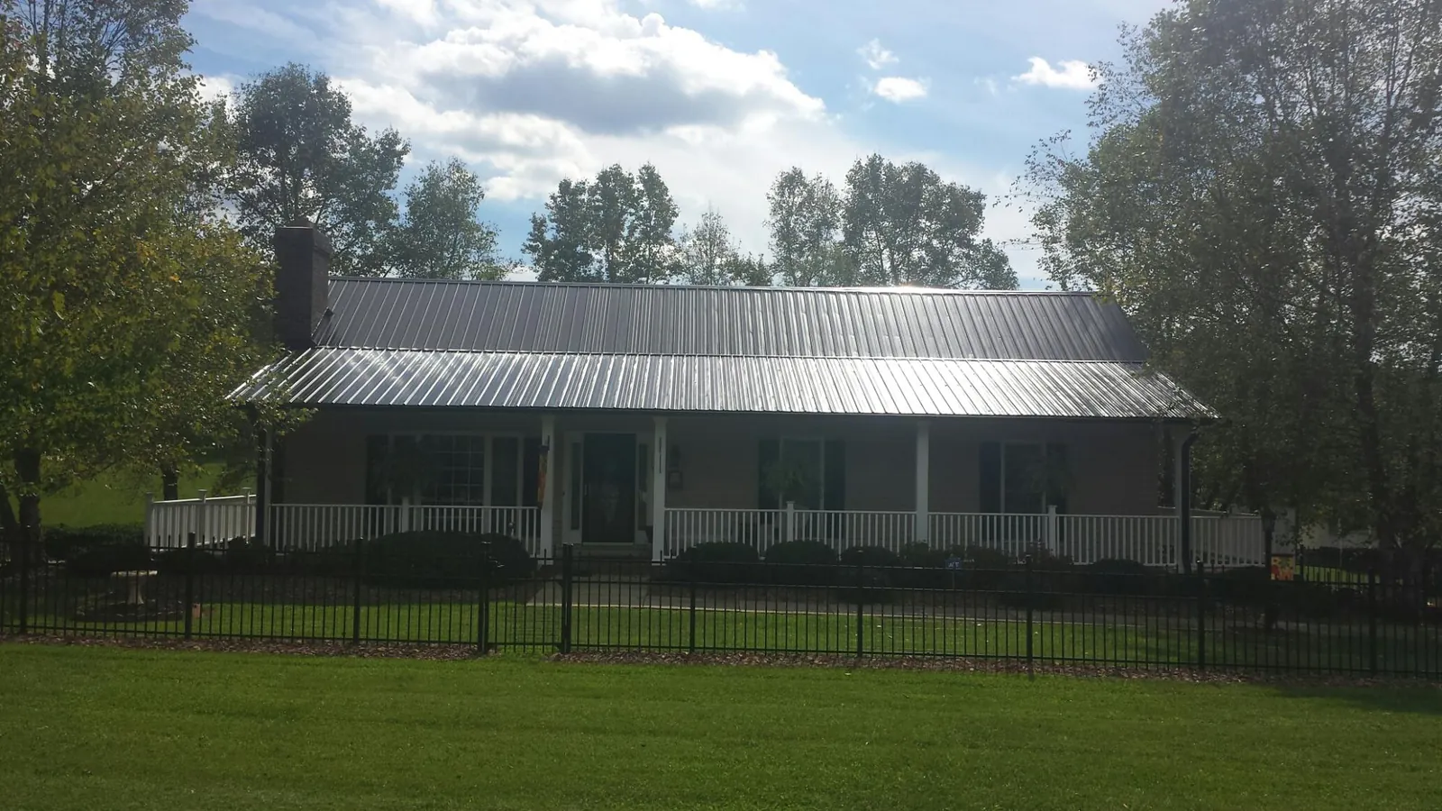 Gray metal roof on a brick ranch with a full width front porch — Gutter Guard Installation work by our crew in Langhorne