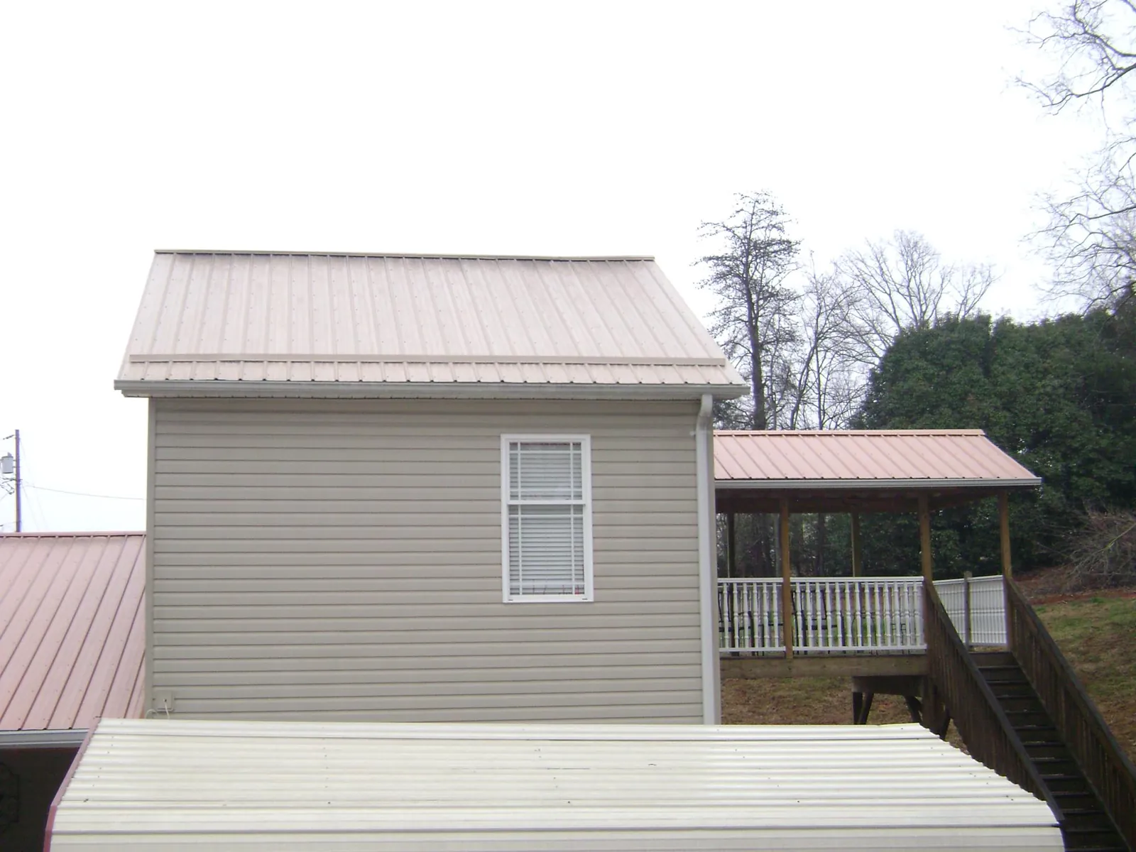 Tan metal roofs on a two story addition and attached porch, from a Roof Replacement job in Langhorne