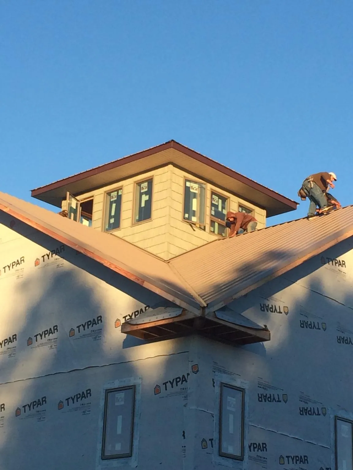 Roofers working around a rooftop cupola on a new metal roof at sunset — Roof Waterproofing in Langhorne by Roofing Brothers